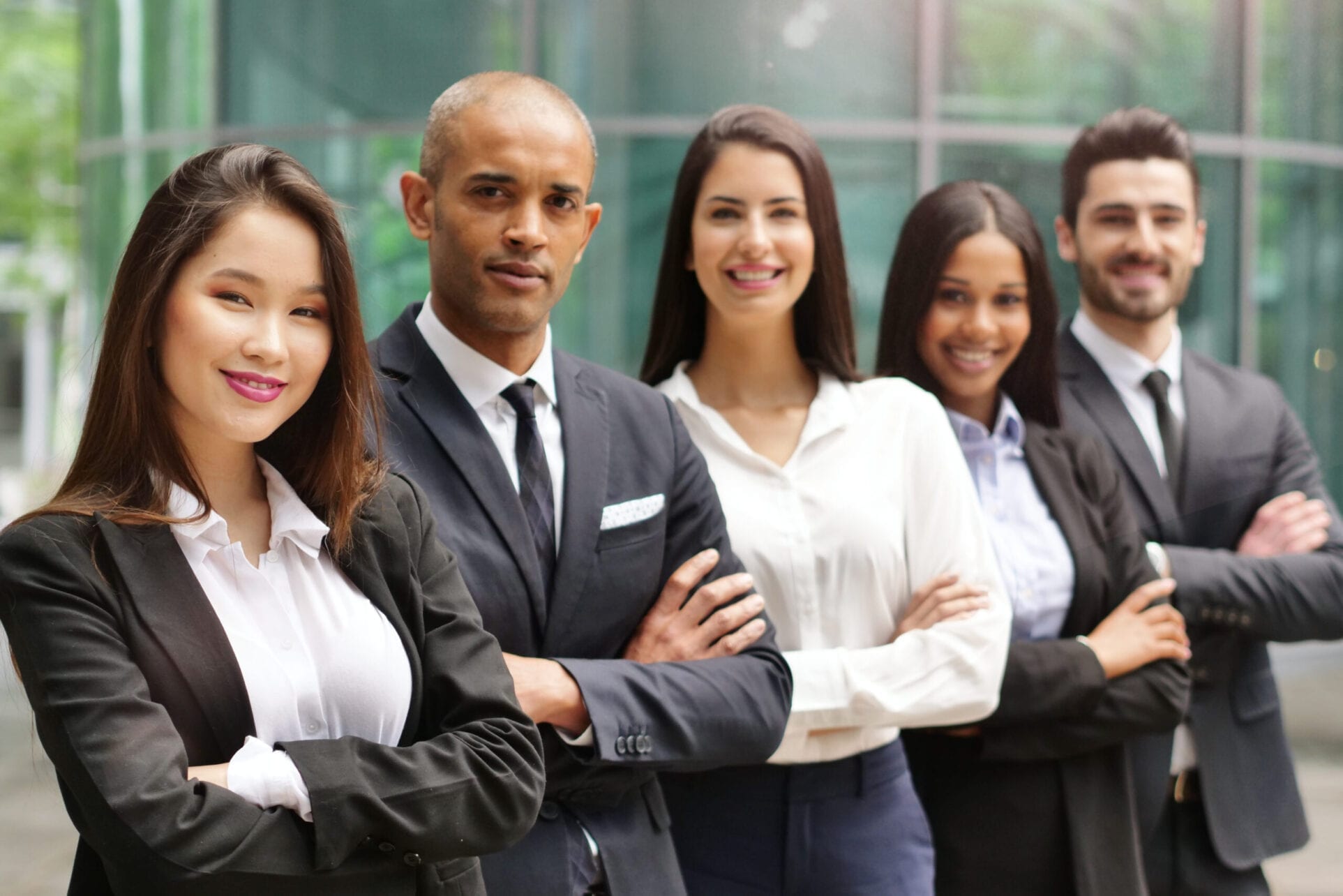 Portrait of business people of different ethnic backgrounds dressed in suits, they smile and cross their arms. Concept of: internationality and career, cooperation and team. Portrait of business people of different ethnic backgrounds dressed in suits, they smile and cross their arms. Concept of: internationality and career, cooperation and team.